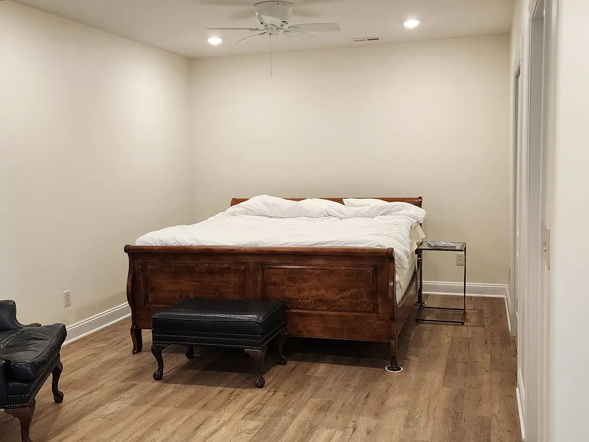 basement remodeling after the work, big vintage wood bed and cream white walls, hardwood floor